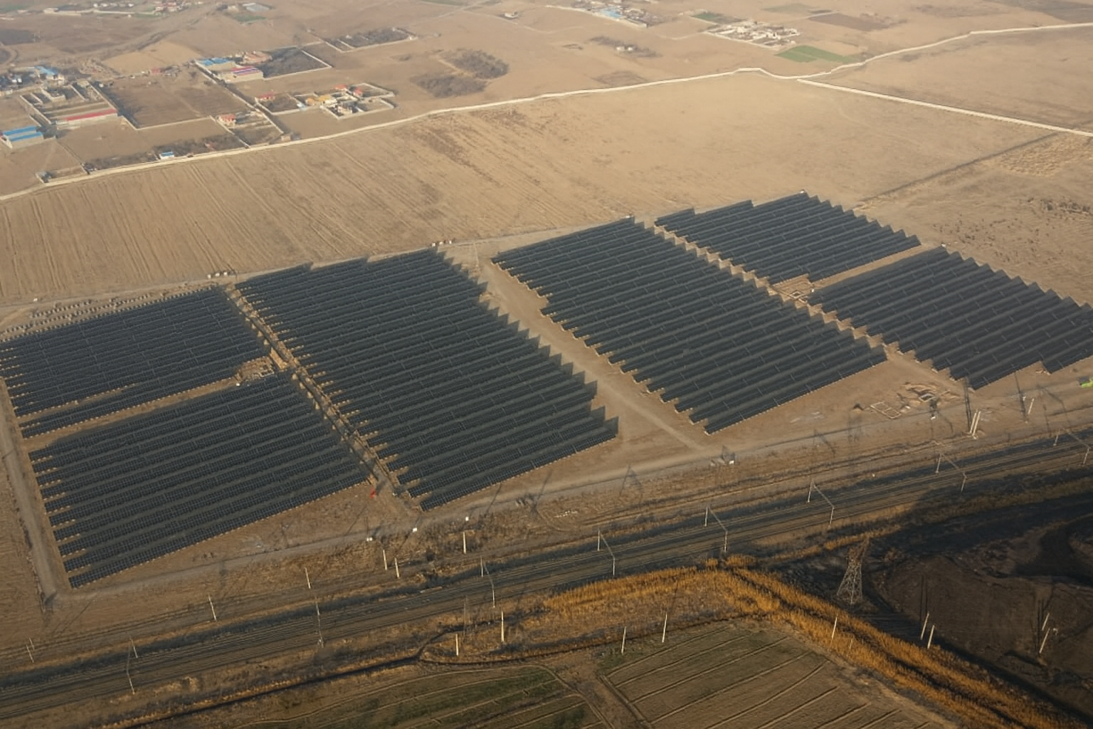 Aerial view of a multi-section solar farm and nearby infrastructure